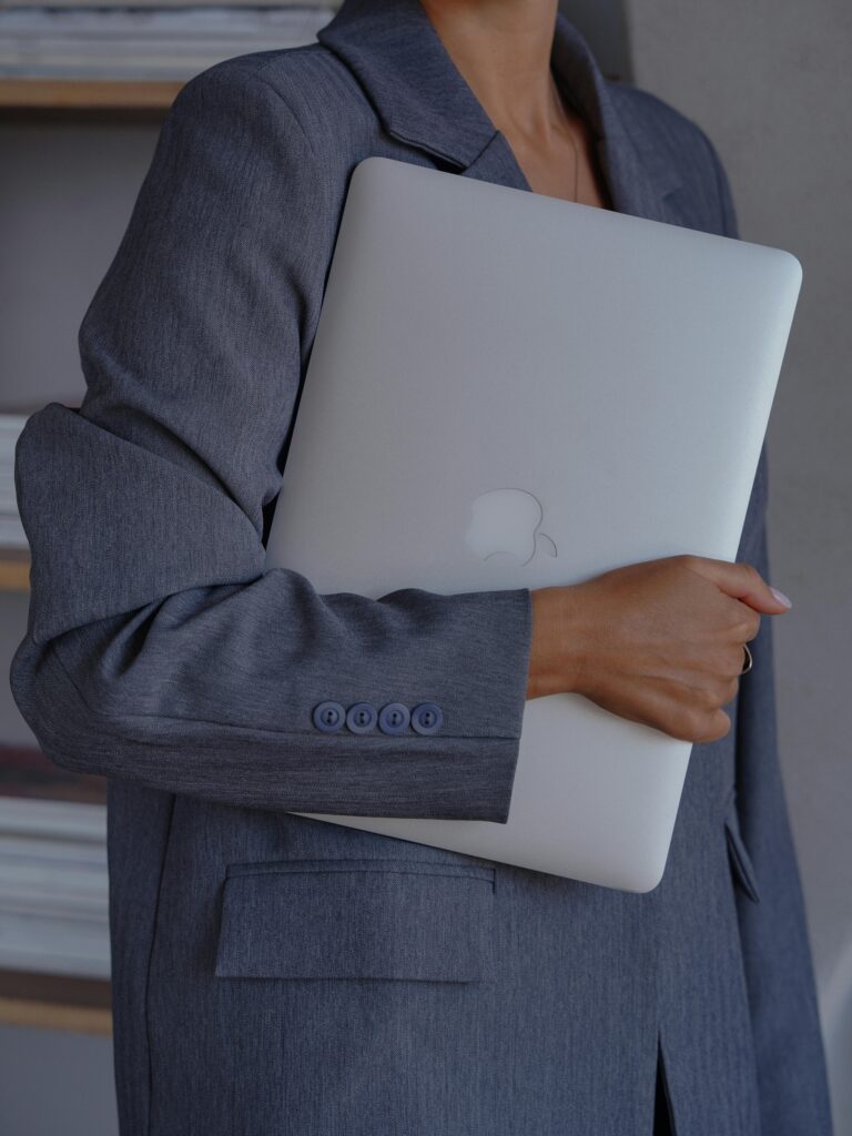 Professional woman holding a laptop in an office setting, expressing elegance and business professionalism.